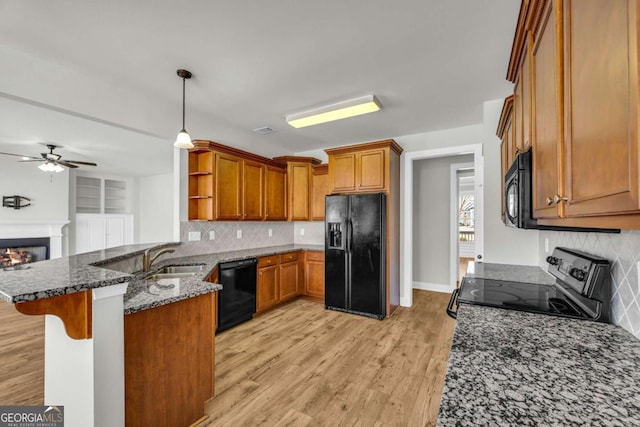 kitchen featuring black appliances, decorative light fixtures, dark stone countertops, kitchen peninsula, and a breakfast bar area