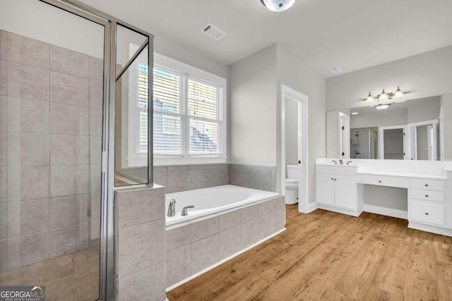 full bathroom featuring wood-type flooring, toilet, vanity, and independent shower and bath