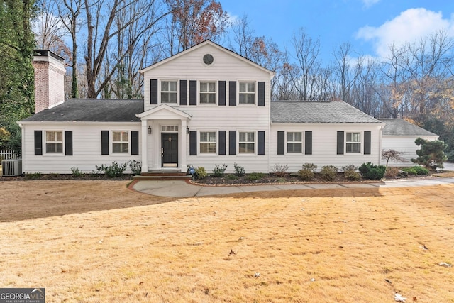 view of front of property with a shingled roof, a chimney, and cooling unit