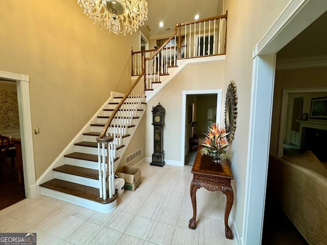 staircase with a towering ceiling, crown molding, and a chandelier