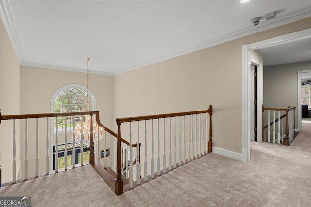 hall featuring crown molding, light carpet, and an inviting chandelier