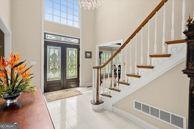 tiled entryway with french doors, a high ceiling, and an inviting chandelier