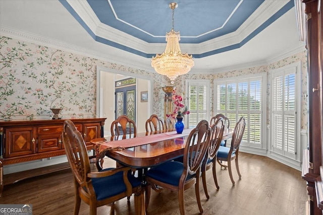 dining space featuring a raised ceiling, wood-type flooring, ornamental molding, and a chandelier