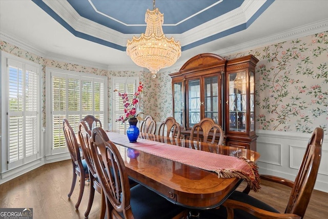 dining area with a notable chandelier, a raised ceiling, and ornamental molding