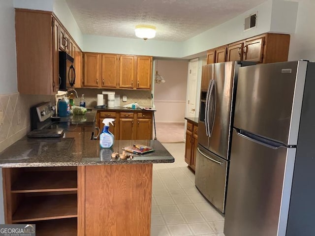 kitchen featuring kitchen peninsula, stainless steel fridge, a textured ceiling, decorative backsplash, and range