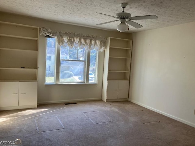 empty room with carpet flooring, a textured ceiling, and a wealth of natural light