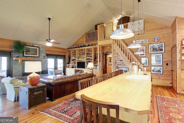 dining area featuring wooden walls, sink, ceiling fan, and light hardwood / wood-style floors