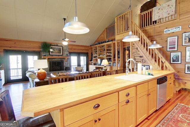 kitchen with dishwasher, wooden walls, butcher block counters, and sink