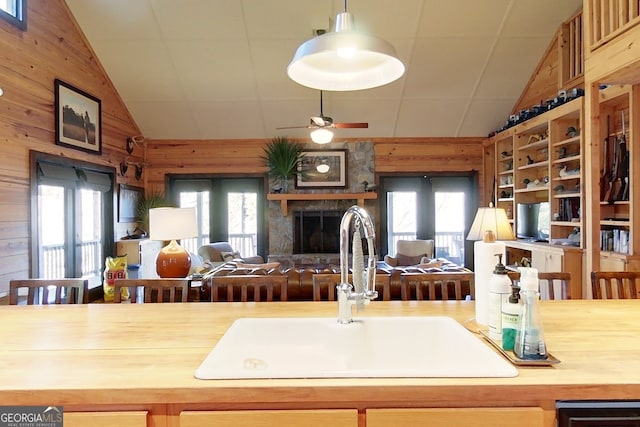 kitchen featuring a fireplace, wood walls, lofted ceiling, and sink