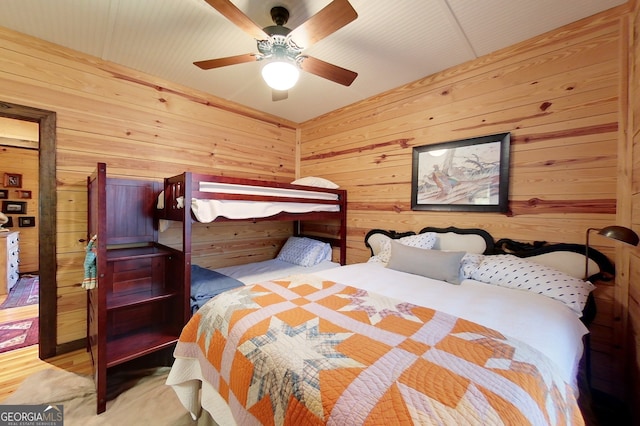 bedroom featuring ceiling fan and wooden walls