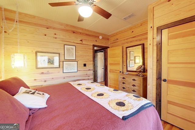 bedroom featuring ceiling fan and wooden walls