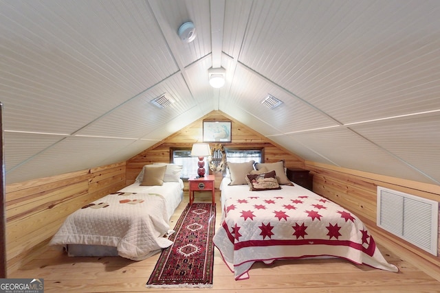 bedroom with wood-type flooring, lofted ceiling, and wood walls