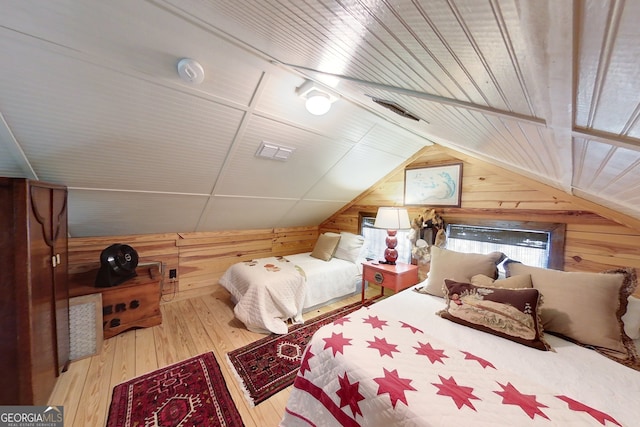 bedroom featuring wooden walls, vaulted ceiling, and hardwood / wood-style flooring