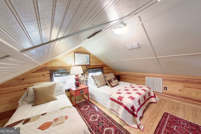 bedroom with hardwood / wood-style floors, lofted ceiling, and wooden walls