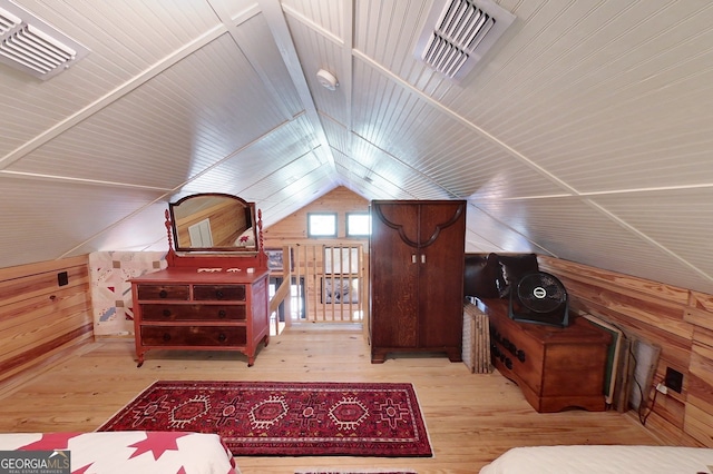 bedroom featuring wood walls, light hardwood / wood-style flooring, and vaulted ceiling