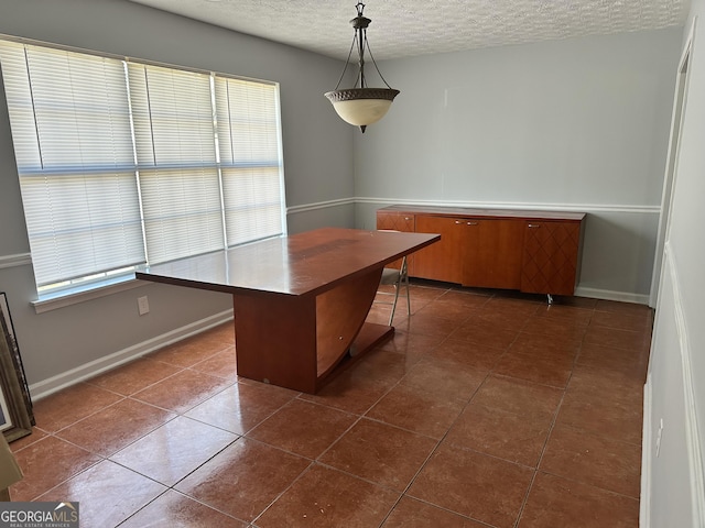 unfurnished office with a textured ceiling, dark tile patterned floors, and plenty of natural light