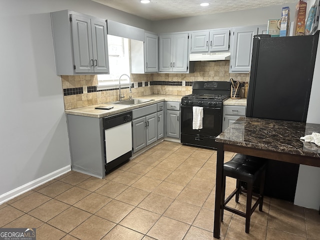 kitchen featuring sink, backsplash, gray cabinets, light tile patterned flooring, and black appliances