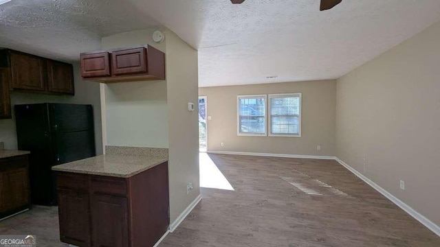 kitchen featuring ceiling fan, black refrigerator, a textured ceiling, and light hardwood / wood-style flooring