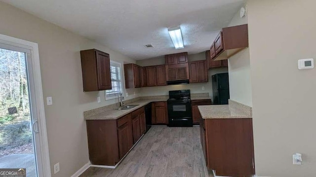 kitchen featuring black appliances, sink, light hardwood / wood-style flooring, a healthy amount of sunlight, and extractor fan