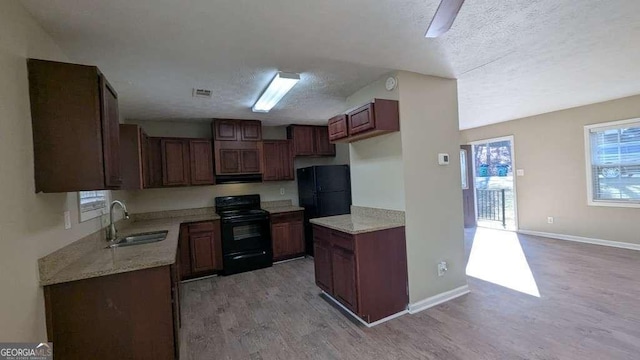 kitchen featuring sink, black appliances, a textured ceiling, and light hardwood / wood-style floors