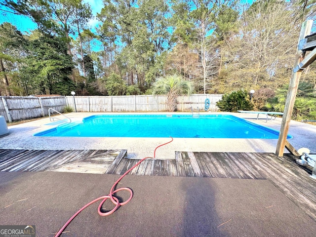 view of pool with a diving board and a patio