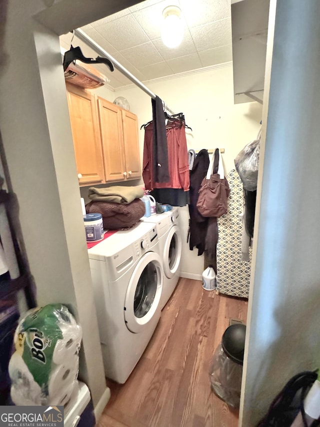 washroom featuring washer and clothes dryer, cabinets, crown molding, and light hardwood / wood-style flooring