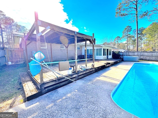 view of swimming pool with a patio area, a sunroom, and a wooden deck