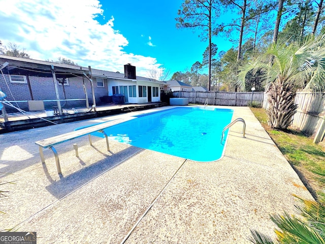 view of swimming pool featuring a patio and a diving board