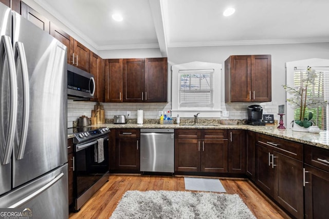 kitchen with light stone countertops, stainless steel appliances, plenty of natural light, and sink