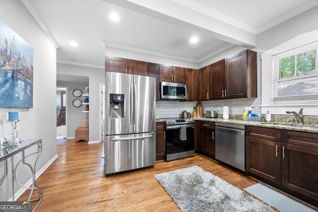 kitchen featuring sink, decorative backsplash, light wood-type flooring, light stone countertops, and appliances with stainless steel finishes