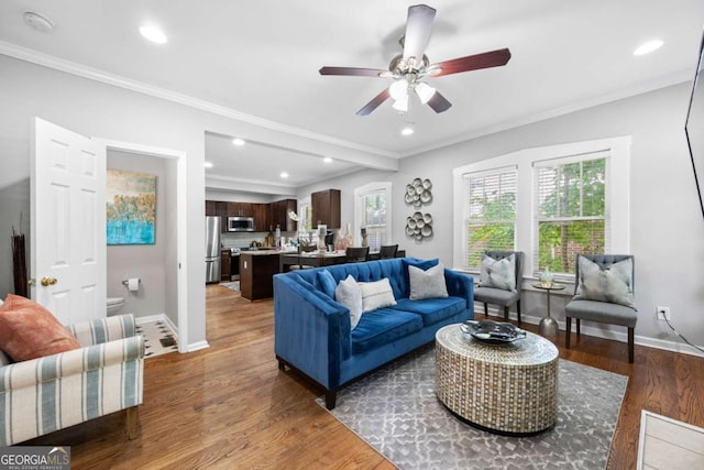 living room with ceiling fan, dark wood-type flooring, and ornamental molding