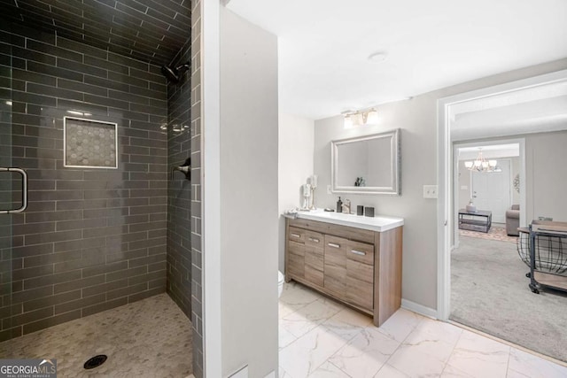 bathroom with a notable chandelier, a tile shower, and vanity