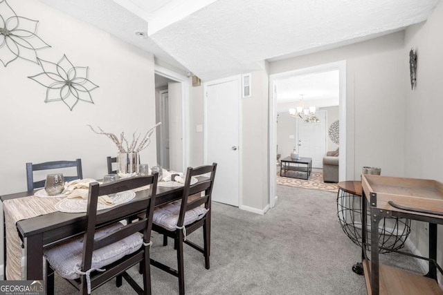 dining area with a notable chandelier, carpet floors, and a textured ceiling