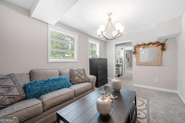 carpeted living room featuring a chandelier and a textured ceiling