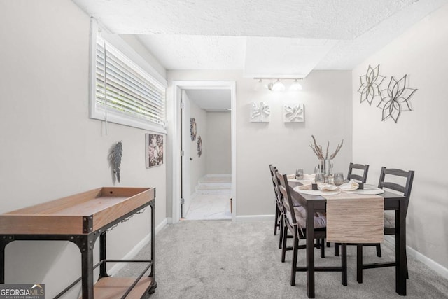 carpeted dining room with a textured ceiling