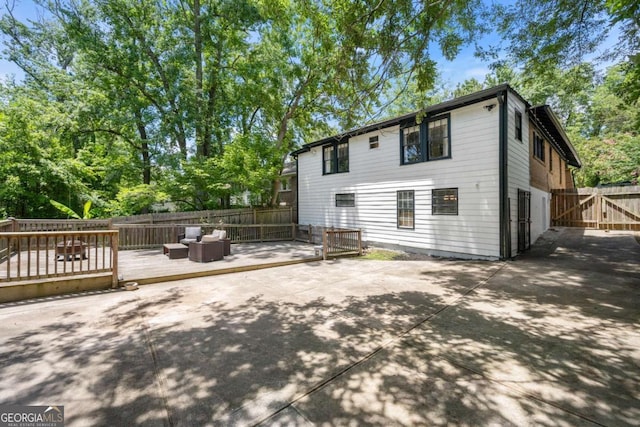 rear view of property with an outdoor living space, a patio, and a deck