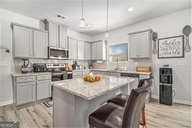 kitchen with sink, decorative light fixtures, a kitchen breakfast bar, a kitchen island, and appliances with stainless steel finishes