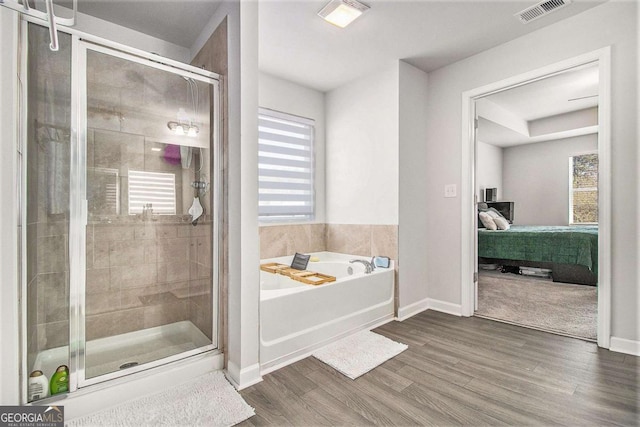 bathroom with a healthy amount of sunlight, shower with separate bathtub, and wood-type flooring