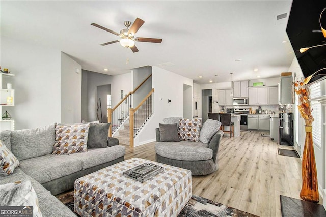 living room with ceiling fan and light hardwood / wood-style flooring