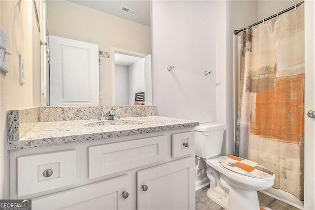 bathroom with toilet, vanity, and hardwood / wood-style floors