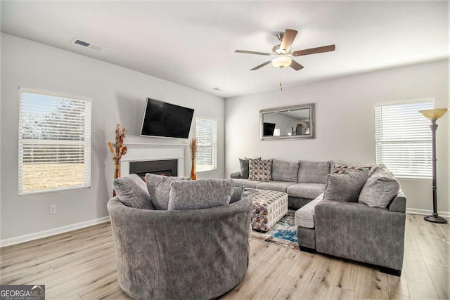 living room featuring light wood-type flooring, ceiling fan, and plenty of natural light