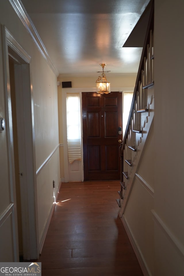 foyer entrance featuring crown molding, dark hardwood / wood-style floors, and an inviting chandelier