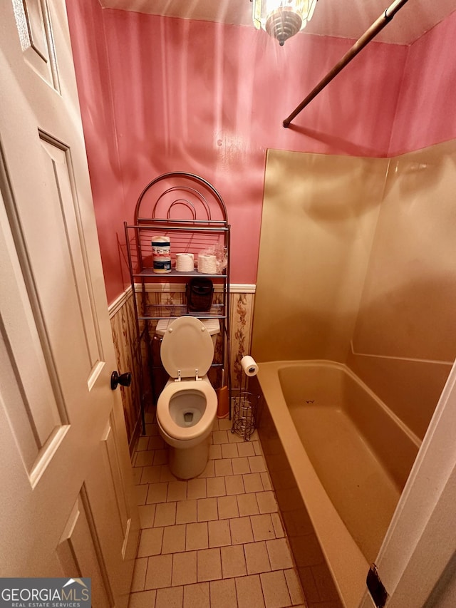 bathroom with toilet, tile patterned floors, and a bath