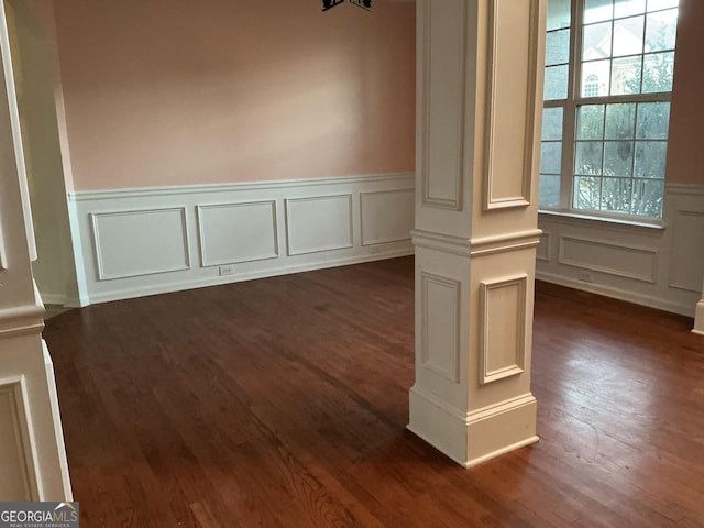 unfurnished room with ornate columns and dark hardwood / wood-style floors