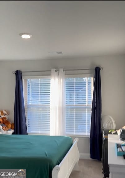 bedroom featuring light carpet and multiple windows