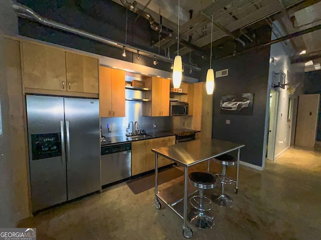 kitchen featuring pendant lighting, stainless steel appliances, a kitchen bar, concrete floors, and sink