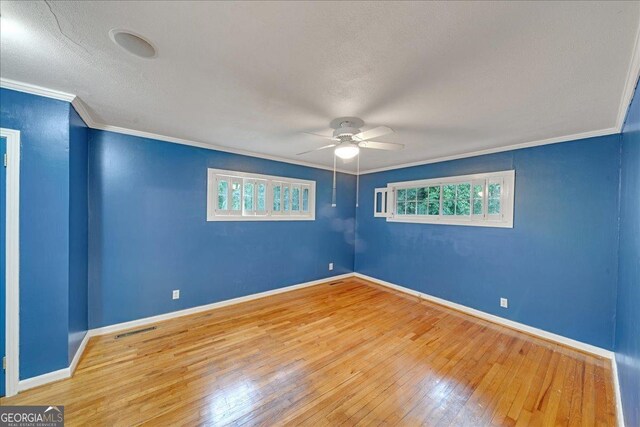 unfurnished living room with light wood-type flooring, ceiling fan with notable chandelier, and ornamental molding