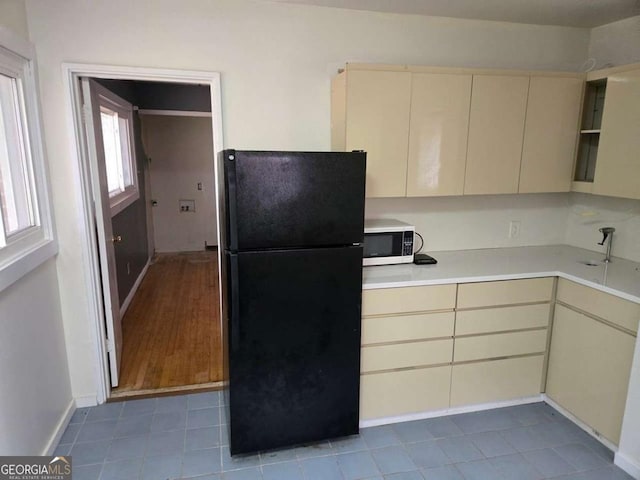 kitchen featuring cream cabinetry and black fridge