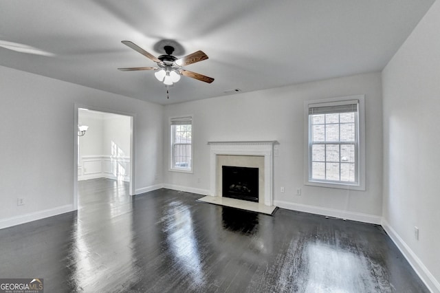 unfurnished living room with a high end fireplace, dark wood-type flooring, and ceiling fan with notable chandelier