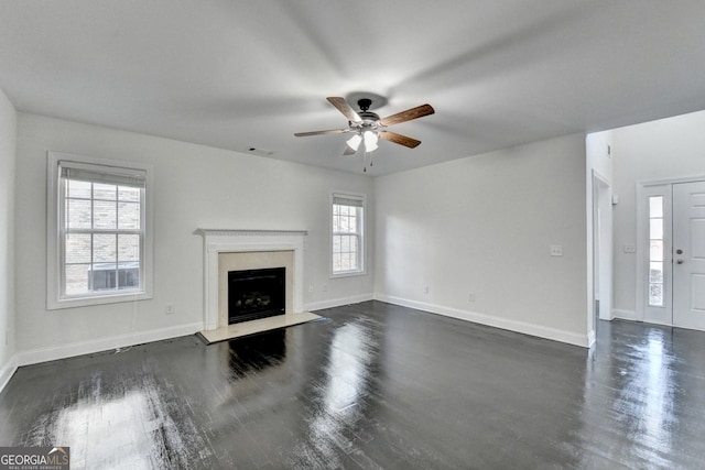 unfurnished living room with a high end fireplace, dark hardwood / wood-style floors, a wealth of natural light, and ceiling fan